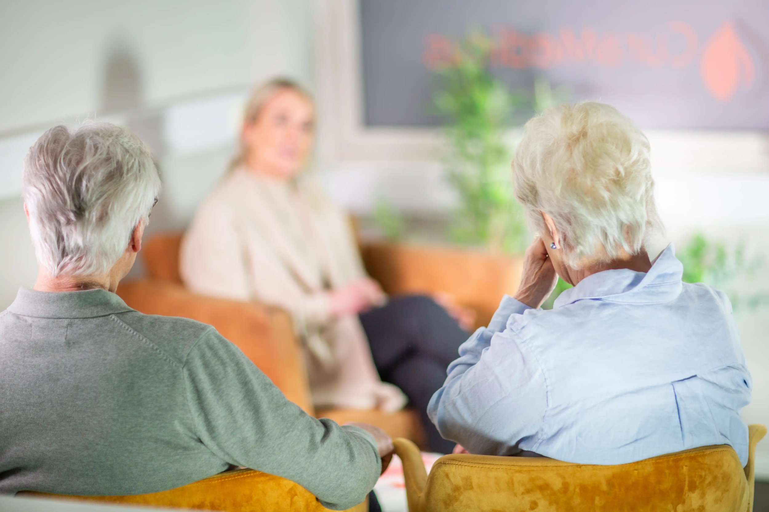 To eldre personer sittende i stol under samtale med terapeut